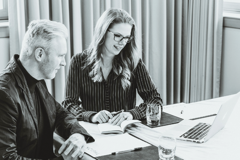 A couple sitting together with a laptop and budgeting notebook, discussing finances in a calm and constructive manner during relationship couples therapy.